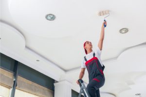 Commercial painter on a ladder painting the ceiling.